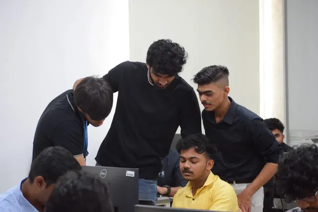 Three people leaning over a participant working at a computer
