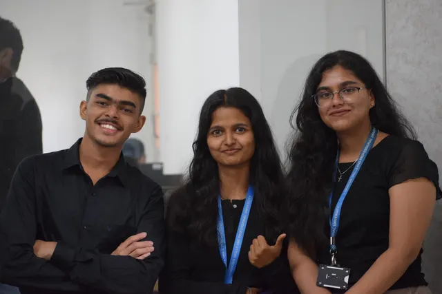 Three people in black smiling, two wearing Symbiosis Skills and Professional University lanyards