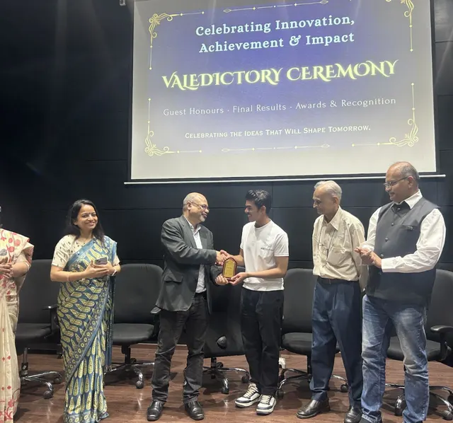 A recognition presentation on stage beneath a valedictory ceremony screen