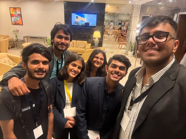 A group selfie of six people in a hotel lobby