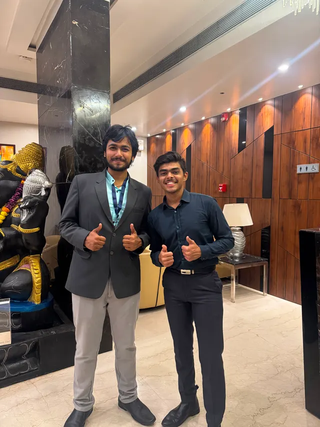 Two people giving a thumbs up in a hotel lobby