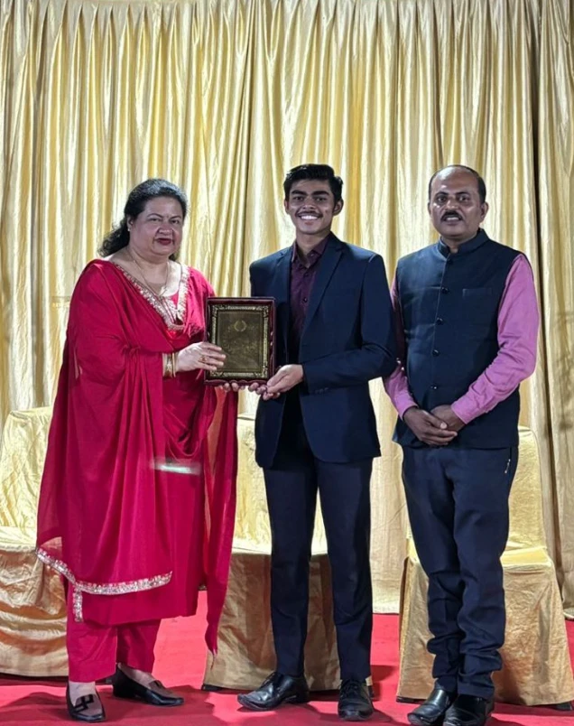 A plaque being presented on stage in front of a gold curtain