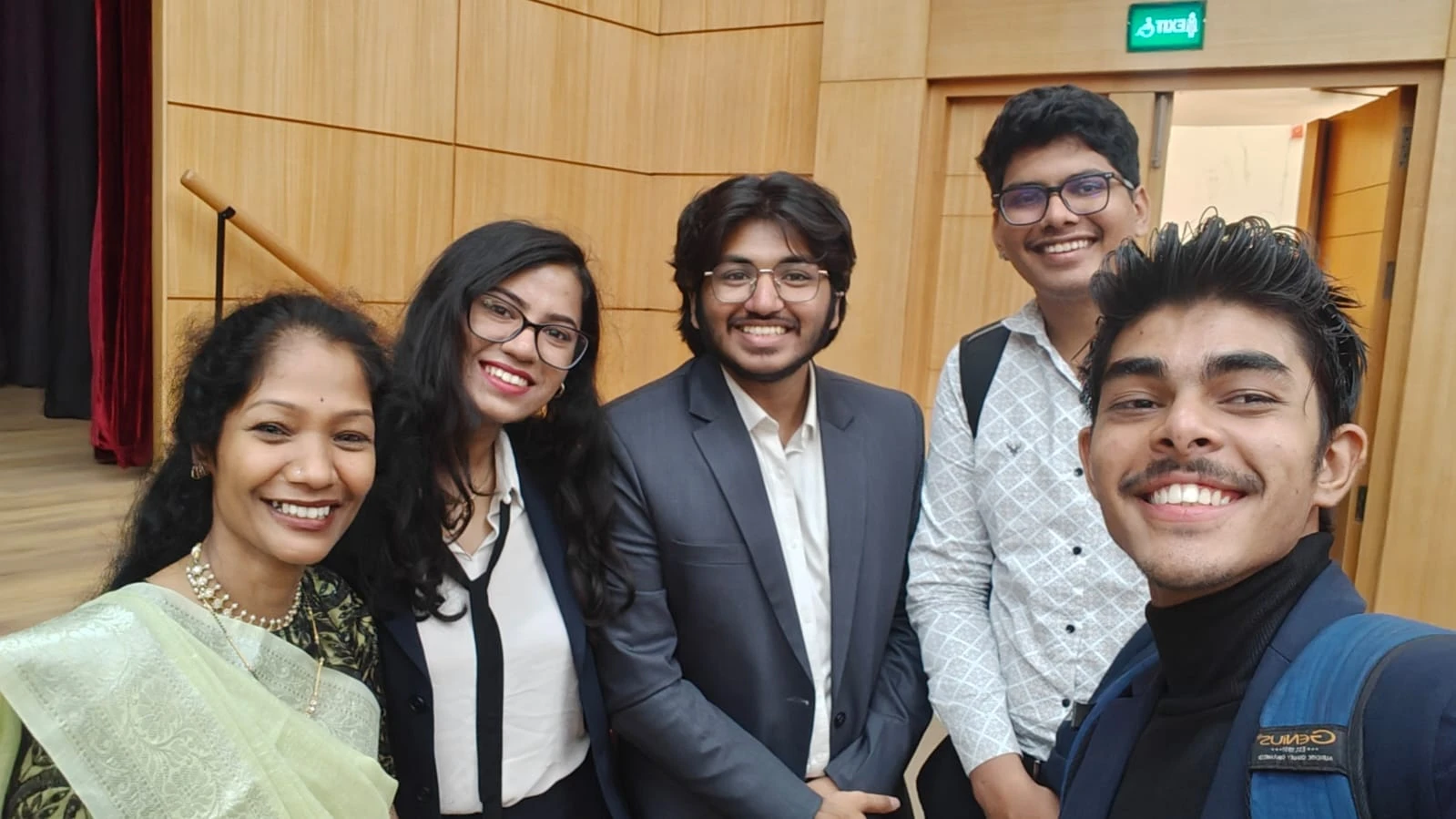 A group selfie of five people in an auditorium