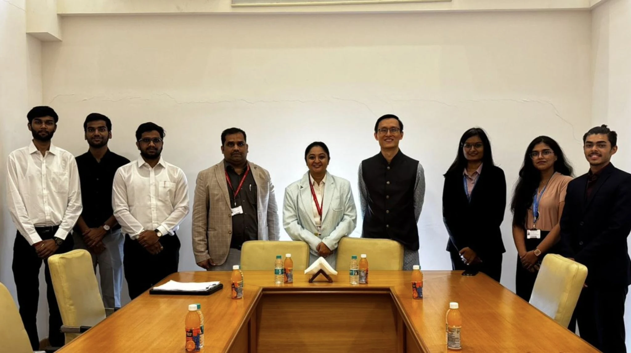 Nine people standing behind a conference table in a meeting room